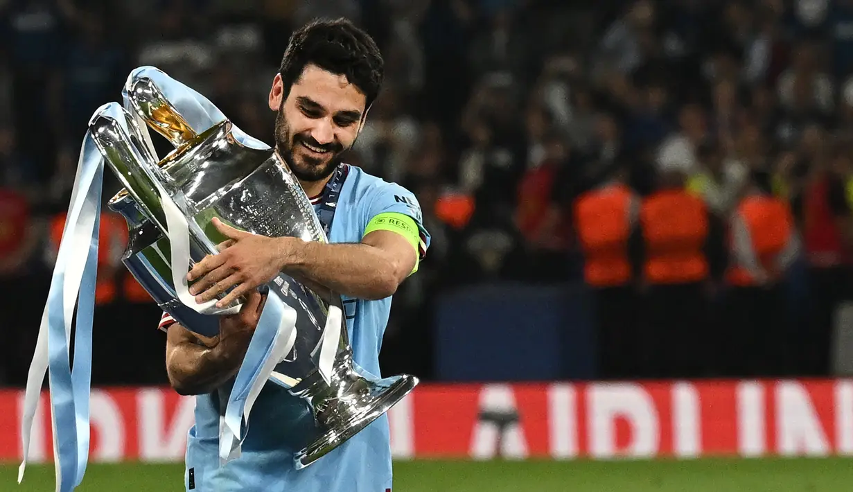 Selebrasi gelandang Manchester City, Ilkay Gundogan dengan memeluk trofi juara dalam perayaan gelar Liga Champions 2022/2023 setelah mengalahkan Inter Milan dalam laga final di Ataturk Olympic Stadium, Istanbul (10/6/2023). Ilkay Gundogan didatangkan Manchester City dari Borussia Dortmund pada awal musim 2016/2017. Jabatan kapten utama baru disandangnya pada awal musim 2022/2023 menggantikan Kevin De Bruyne. Setelah 7 musim, ia meninggalkan The Citizens untuk bergabung dengan Barcelona mulai musim 2023/2024. (AFP/Paul Ellis)