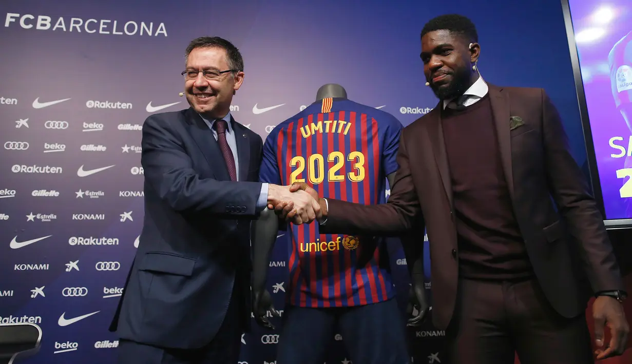 Bek Prancis, Samuel Umtiti dan Presiden Barcelona Josep Maria Bartomeu bersalaman pada pengumuman perpanjangan kontraknya di Camp Nou, Senin (4/6). Umtiti mendapatkan kontrak baru, yang akan mengikatnya di Camp Nou hingga 2023. (AP/Manu Fernandez)