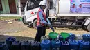 Relawan Palang Merah Indonesia (PMI) Kabupaten Bangkalan mengisi air bersih ke dalam jeriken milik warga di Dusun Batangan Tengah, Desa Batangan, Kecamatan Tanah Merah, Kabupaten Bangkalan, Jawa Timur, Selasa (21/7/2026). (AFP/ Juni Kriswanto)
