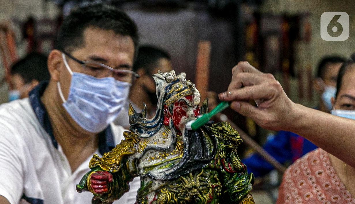 Para jemaat menyikat patung yang ada di Vihara Amurva Bhumi, Jakarta, Kamis (4/2/2021). Ritual mencuci patung dewa serta bersih-bersih ini dilakukan dalam rangka menyambut perayaan Tahun Baru Imlek 2572. (Liputan6.com/Faizal Fanani)