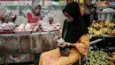 Seorang wanita menghitung uang kertas untuk membayar pembelian daging ayam di sebuah warung pinggir jalan di Jakarta pada Sabtu 8 November 2025. Pemerintah berupaya menjaga momentum agar rata-rata pertumbuhan ekonomi tahun ini bisa mencapai 5,2 persen. (YASUYOSHI CHIBA/AFP)