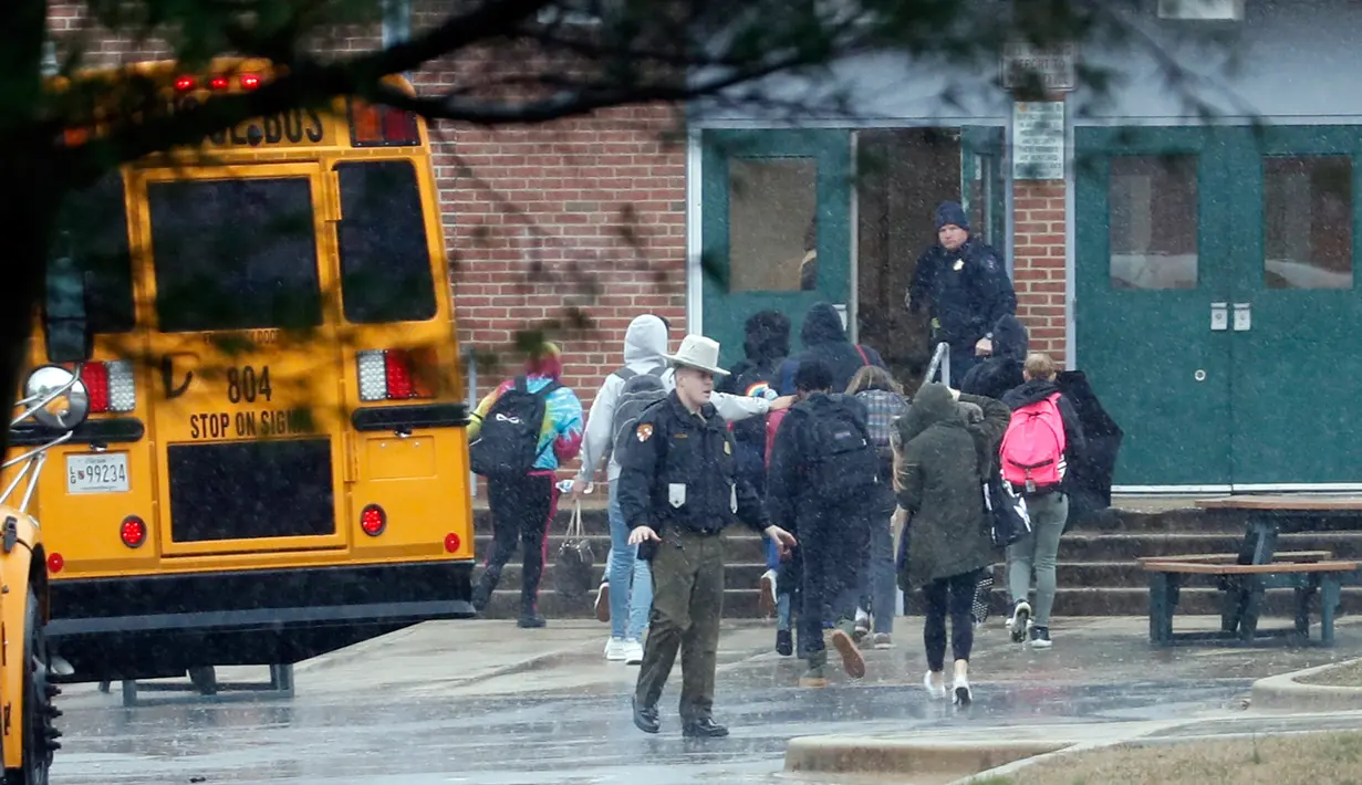 Petugas keamanan setempat memindahkan siswa menjauhi lokasi penembakan di Great Mills High School di Maryland, AS (20/3). Saat ini, sekolah masih ditutup untuk sementara waktu. Para siswa dievakuasi ke sekolah terdekat. (AP Photo / Alex Brandon)