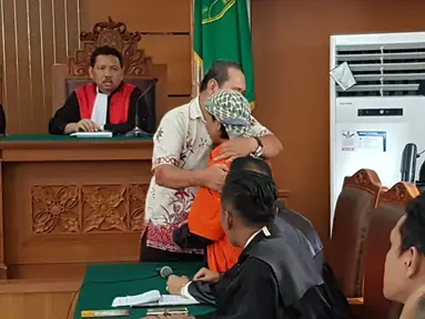 Korban ledakan bom di Jalan MH Thamrin pada Januari 2016, Ipda Denny Mahieu memeluk terdakwa Aman Abdurrahman di PN Jakarta Selatan, Jumat (23/2). Ipda Denny menjadi saksi kasus terorisme dengan terdakwa Aman Abdurrahman. (Liputan6.com/Ady Anugrahadi)