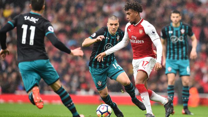 Striker Arsenal, Alex Iwobi, berusaha melewati kepungan pemain Southampton pada laga Premier League di Stadion Emirates, London, Minggu (8/4/2018). Arsenal menang 3-2 atas Southampton. (AFP/Glyn Kirk)