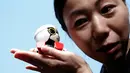 Seorang wanita memegang Robot Mini Kirobo saat diperkenalkan di Tokyo, Jepang pada 27 September 2016. Toyota masih menggembangkan keterampilan Kirobo Mini agar memiliki lebih banyak kemampuan. (REUTERS/Kim Kyung-Hoon)