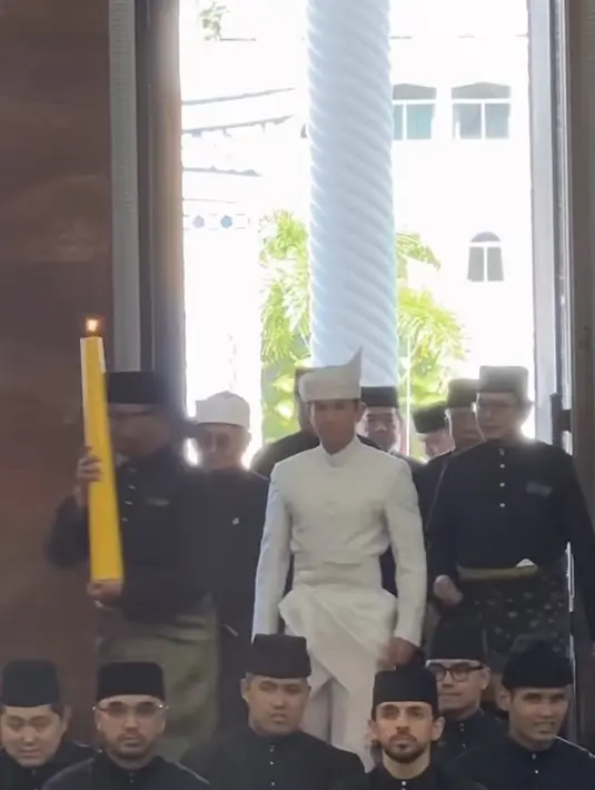 Memasuki Masjid Omar Ali Saifuddin, pangeran Mateen didampingi para tetua yang mengenakan baju hitam. Dengan lilin kuning besar tepat di depannya. [@qnph.bn]