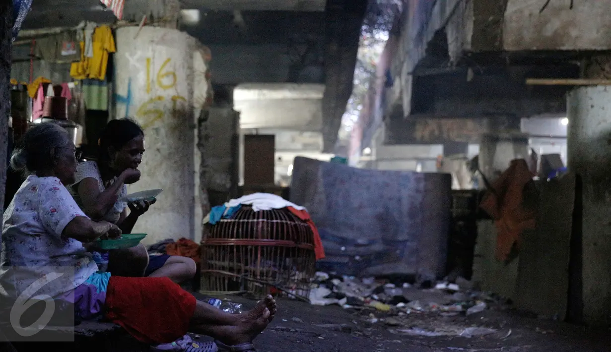 Dua wanita tengah makan di pemukiman kolong jalan tol Ir Wiyoto Wiyono, Penjaringan, Jakarta, Minggu (13/3). Pemprov DKI berencana menggusur sebanyak delapan Rukun Warga (RW) yang menghuni kolong tol tersebut. (Liputan6.com/Faizal Fanani)