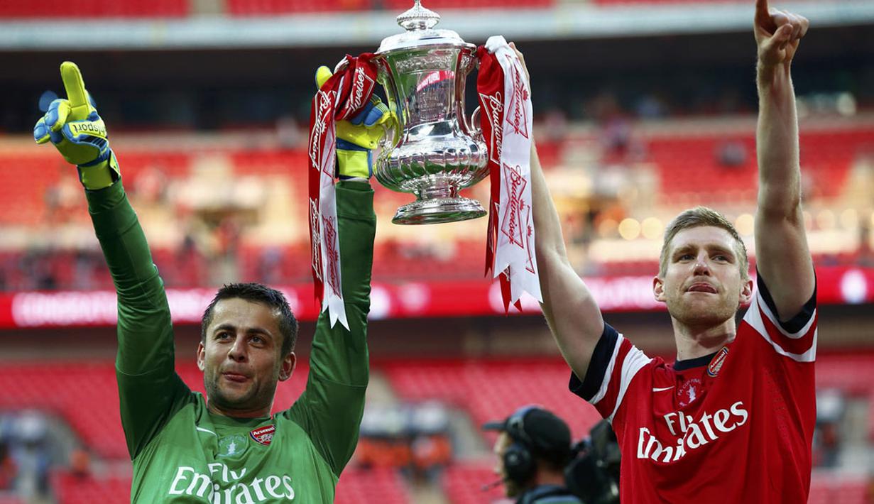 Penjaga gawang Arsenal, Lukasz Fabianski (kiri) bersama Per Mertesacker mengangkat trofi Piala FA usai menumbangkan Hull City 3-2 di Stadion Wembley, London, (18/5/2014). (REUTERS/Darren Staples)