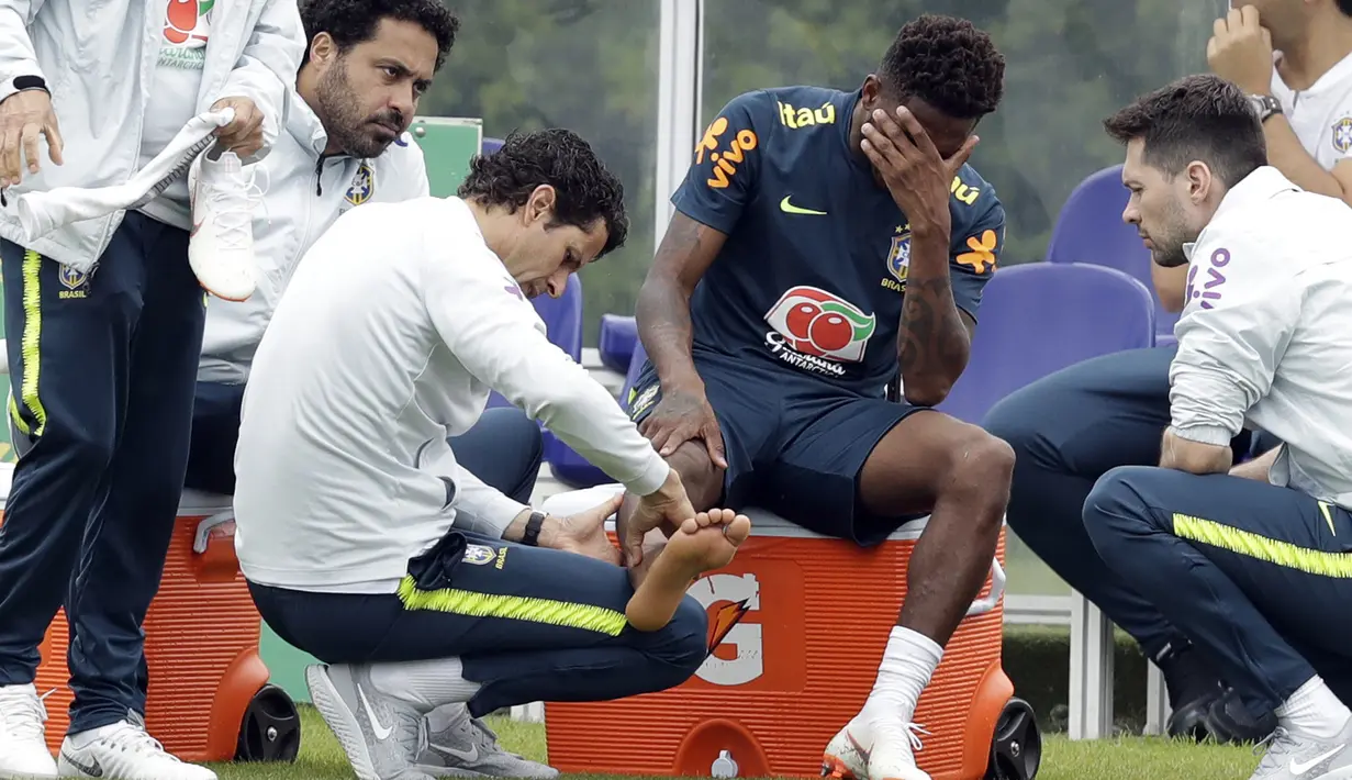 Pemain Brasil, Fred menahan sakit saat diperiksa dokter tim di lapangan latihan Tottenham Hotspur football club, Inggris, (7/6/2018). Fred mengalami masalah di engkel kaki. (AP/Matt Dunham)