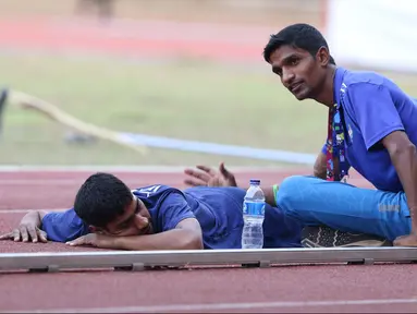 Salah satu atlet Asian Para Games 2018 dari India mendapat pijatan dari rekannya di Stadion Madya Kompleks Gelora Bung Karno, Jakarta, Kamis (11/10). Berbagai aktivitas dilakukan para atlet para atletik di luar arena. (Liputan6.com/Helmi Fithriansyah)