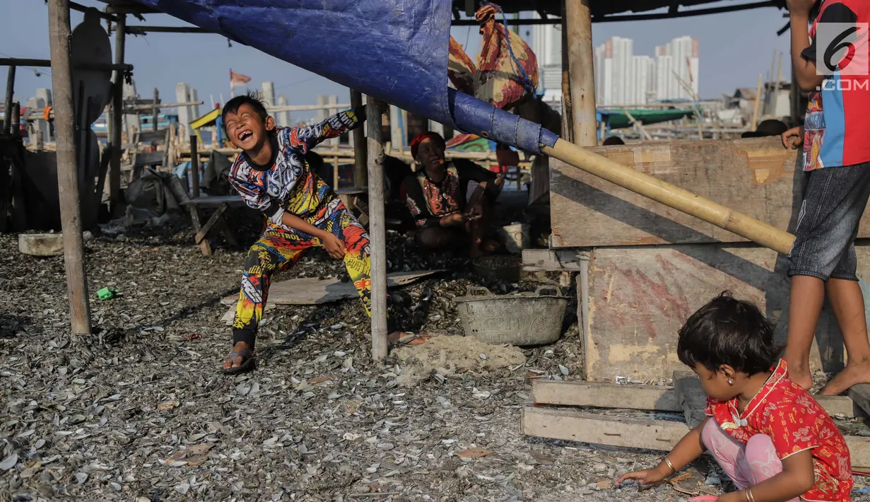 Anak-anak bermain sembari menemani ibunya mengupas kerang hijau di Kampung Nelayan Muara Angke, Jakarta, Rabu (3/7/2019). Dengan penghasilan rata-rata Rp 30 ribu/hari, para buruh pengupas kerang hijau tersebut harus cukup memenuhi kebutuhan hidup keluarganya. (Liputan6.com/Faizal Fanani)