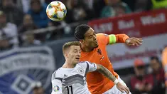 Bek Belanda, Virgil Van Dijk berebut bola udara dengan gelandang Jerman, Marco Reus selama pertandingan grup C  kualifikasi Euro 2020 di Hamburg, Jerman (6/9/2019). Belanda menang telak 4-2 atas Jerman. (AP Photo/Martin Meissner)