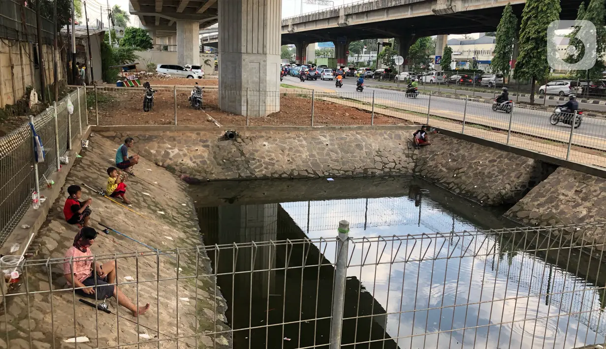 Sejumlah warga memancing ikan di kubangan yang berada di Jalan DI Panjaitan, Jatinegara, Jakarta, Selasa (16/6/2020). Meski telah dipagari, sejumlah warga tetap memancing ikan di lokasi yang merupakan saluran pembuangan tersebut. (Liputan6.com/Immanuel Antonius)