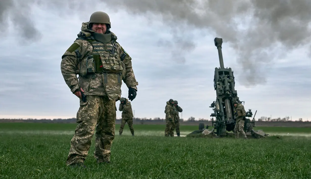 Seorang tentara Ukraina tersenyum ketika Howitzer M777 yang dipasok Amerika Serikat menggempur posisi Rusia dari wilayah Kherson, Ukraina, 9 Januari 2023. Memasuki hari ke-321 peperangan, konflik di antara Rusia dengan Ukraina sampai saat ini terus berlanjut dan belum terlihat akan segera berakhir. (AP Photo/Libkos)