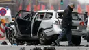 Petugas kepolisian memeriksa bangkai mobil Volkswagen yang rusak di Berlin , Jerman, (15/3).Kepolisian Jerman mengatakan bahwa penyebab meledaknya mobil tersebut disebabkan oleh bahan peledak. (REUTERS / Fabrizio Bensch)