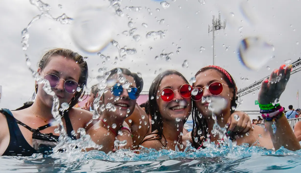 Sejumlah wanita bersuka ria mencipratkan air di kolam renang selama Festival Arenal Sound di Burriana, Spanyol (31/7/2019). Festival musik ini berlangsung dari 30 Juli sampai 4 Agustus 2019.  (AFP Photo/Jose Jordan)