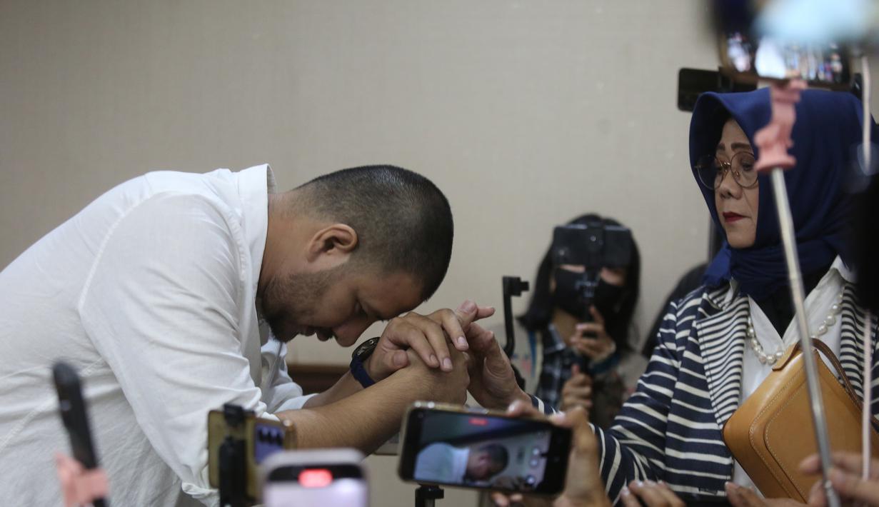 Ammar Zoni menjadi terdakwa karena diduga terlibat dalam peredaran narkotika di dalam Lapas Salemba, Jakarta. Tampak dalam foto, Pesohor Muhammad Ammar Akbar alias Ammar Zoni mencium tangan ibu angkatnya saat dihadirkan secara langsung pada persidangan terkait kasus peredaran narkotika di dalam Lembaga Pemasyarakatan (Lapas) Salemba di Pengadilan Negeri Jakarta Pusat, Kamis (18/12/2025). (merdeka.com/Arie Basuki)