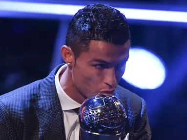 Bintang Real Madrid, Cristiano Ronaldo, mencium trofi pemain terbaik FIFA 2017 di London, Senin (23/10/2017) Ronaldo berhasil mengalahkan Lionel Messi dan Neymar yang juga menjadi nominasi. (AFP/Ben Stansall)