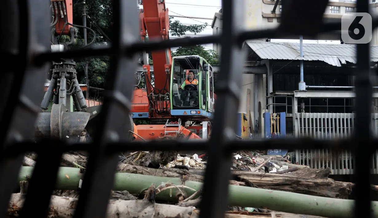 Petugas menggunakan alat berat saat mengangkut tumpukan sampah kiriman di Pintu Air Manggarai, Jakarta, Minggu (29/12/2019). Jenis sampah yang memenuhi Pintu Air Manggarai seperti batang pohon, balok kayu, plastik, hingga limbah rumah tangga. (merdeka.com/Iqbal Nugroho)