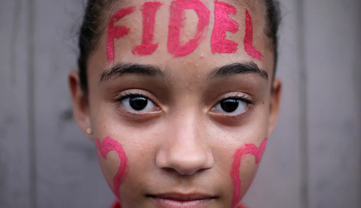 Seorang anak perempuan melukis wajah mereka dengan tulisan Fidel di Bayamo, Kuba (3/11). Mereka melakukan hal tersebut sebagai bentuk penghormatan kepada mendiang Fidel Castro (Reuters/Enrique De La Osa)