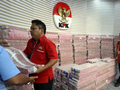 Petugas mengangkut uang dari tumpukan sebesar Rp 300 miliar yang dipamerkan di gedung Merah Putih Komisi Pemberantasan Korupsi (KPK), Jakarta, Kamis (20/11/2025). Komisi Pemberantasan Korupsi (KPK) memamerkan uang tunai sebesar Rp 300 miliar. (Liputan6.com/Helmi Fithriansyah)