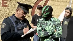 Polisi Mexico mengintrogasi aktivis yang memakai topeng dan kostum bermotif ganja di depan Komisi Federal untuk Perlindungan terhadap Risiko Sanitary (COFEPRIS), Mexico (20/11). Mahkamah Agung Meksiko melegalkan jenis ganja baru. (AFP PHOTO/Yuri CORTEZ)