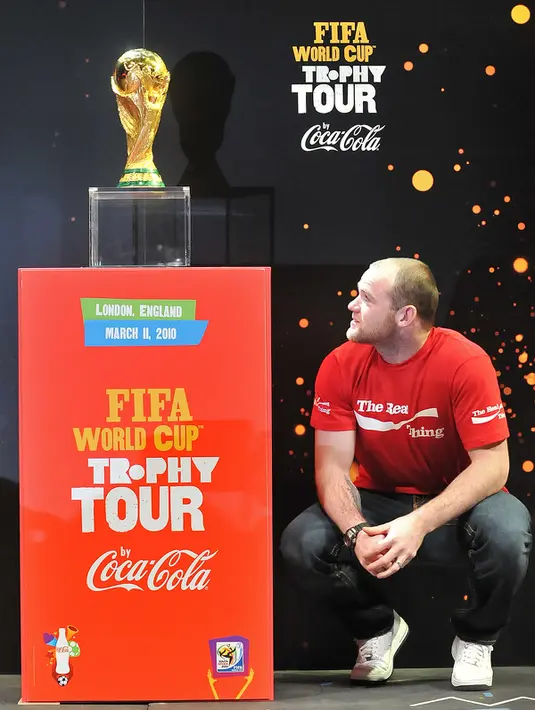 Pemain Manchester United, Wayne Rooney terlihat jongkok melihat piala dunia di Earls Court, London, pada 11 Maret 2010. (AFP PHOTO / Carl de Souza)
