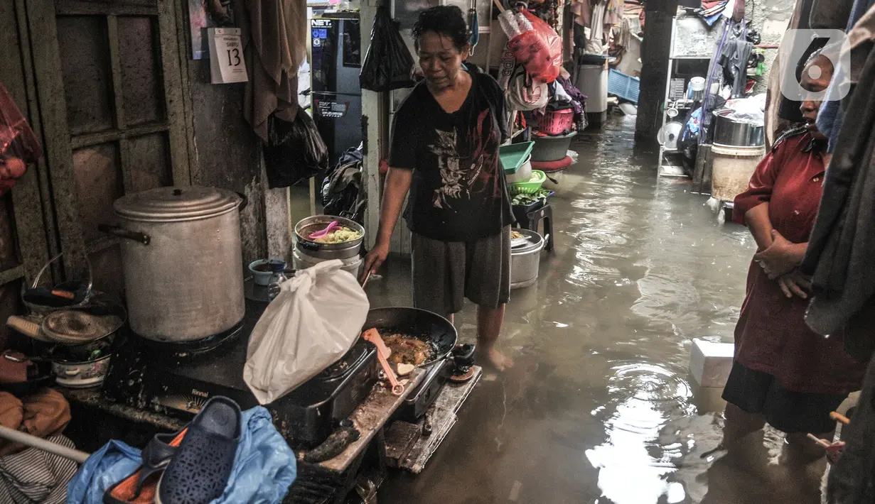 Warga memasak di tengah banjir yang merendam permukiman di Bukit Duri, Jakarta, Kamis (18/2/2021). Hujan deras yang mengguyur sejak pagi menyebabkan permukiman warga di 5 RW, yakni RW 03, 04, 05, 06, dan 07 Kelurahan Bukit Duri terendam banjir. (merdeka.com/Iqbal S Nugroho)