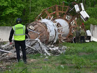 Seorang penyelidik Kepolisian Ukraina memeriksa puing-puing di tower atau menara Televisi (TV) Kharkiv, setelah para pejabat melaporkan serangan Rusia terhadap menara tersebut, di pinggiran Kharkiv, Senin (22/4/2024). (SERGEY BOBOK / AFP)