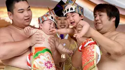 Dua pesumo menggendong bayi yang menangis selama Festival Nakizumo atau kontes bayi menangis di kuil Kamegaike-Hachiman, Jepang, Minggu (14/5). Festival lebih dari 400 tahun ini sudah berlangsung turun-temurun dari leluhur. (Toru YAMANAKA/AFP)