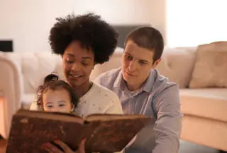 Ilustrasi orangtua yang sedang membaca buku dengan anak (sumber foto: pexels.com/Andrea Piacquadio)