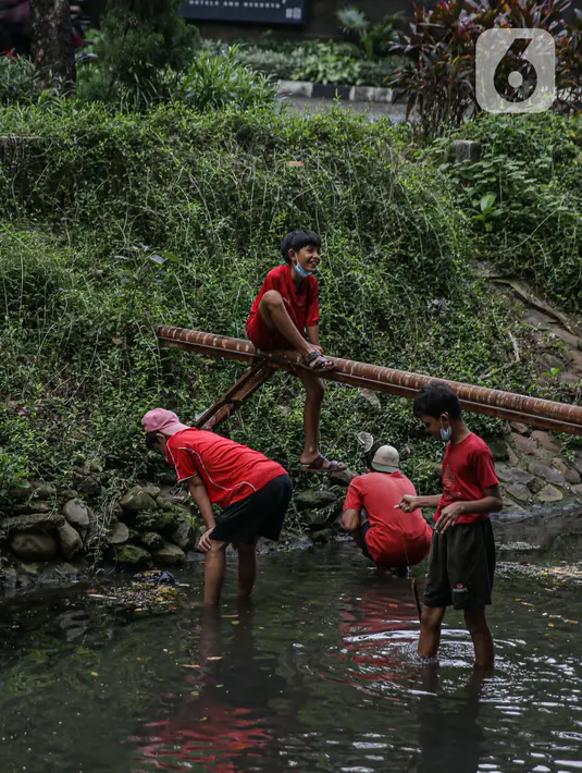 Anak-anak bermain saat mencari belut di anak kali menteng, Jakarta, Selasa (8/6/2021). Ruang bermain anak-anak di Jakarta kian terbatas. Terbatas lahan bermain membuat anak-anak Jakarta bermain ditempat yang tak semestinya demi mencari kesenangan. (Liputan6.com/Faizal Fanani)