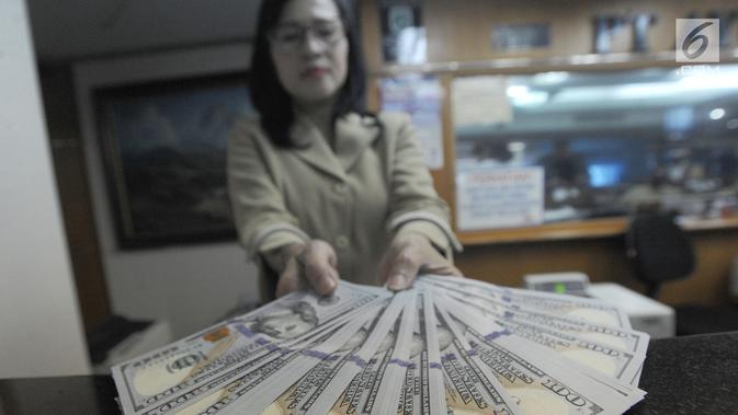 Petugas menunjukkan uang dolar AS di gerai penukaran mata uang di Ayu Masagung, Jakarta, Senin (13/8). Pada perdagangan jadwal pekan, senin (13/08). Nilai tukar rupiah terhadap dolar AS menyentuh posisi tertingginya Rp 14.600. (Merdeka.com/Arie Basuki)