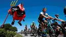 Pebalap sedang melewati Didi Senft, seorang penggemar balap sepeda yang dikenal dengan nama 'El Diablo' (The Devil) di Etape 7 Tour de France yang berjarak 190.5-km dari Livarot ke Fougeres, Prancis, (10/7/2015). (REUTERS/Eric Gaillard)