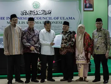Ketua Dewan Masjid Indonesia Jusuf Kalla (ketiga kiri) bersama Wakil Ketua Umum MUI Muhyiddin Junaidi (ketiga kanan) menunjukan surat fatwa Nomor 14 Tahun 2020 Tentang Penyelenggaraan Ibadah dalam Situasi Terjadi Wabah Covid-19, di Kantor MUI Jakarta, Selasa (17/3/2020). (Liputan6.com/Faizal Fanani)