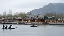 Seorang awak perahu Kashmir mengangkut penumpang saat hujan di Danau Dal di Srinagar (20/3). Danau Dal yang luas dan bening. Diatasnya terhampar gerombolan daun bunga lotus. (AFP Photo/Tauseef Mustafa)