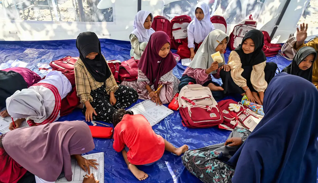 Belum terlihat tanda-tanda pembersihan lumpur baik di luar maupun di dalam ruangan belajar. Tampak dalam foto, para siswa berkumpul di kelas darurat di dalam tempat penampungan setelah sekolah mereka hancur akibat banjir bandang di daerah yang berdekatan dengan Sungai Peusangan di Bireuen, provinsi Aceh, Senin 5 Januari 2026. (CHAIDEER MAHYUDDIN/AFP)