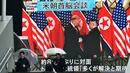 Pejalan kaki berjalan di depan layar besar yang menyiarkan pertemuan Presiden AS Donald Trump dan pemimpin Korea Utara Kim Jong Un di Tokyo (28/2). Dalam pertemuan tersebut Trump dan Kim membahas perundingan terkait nuklir. (AFP Photo/Kazuhiro Nogi)