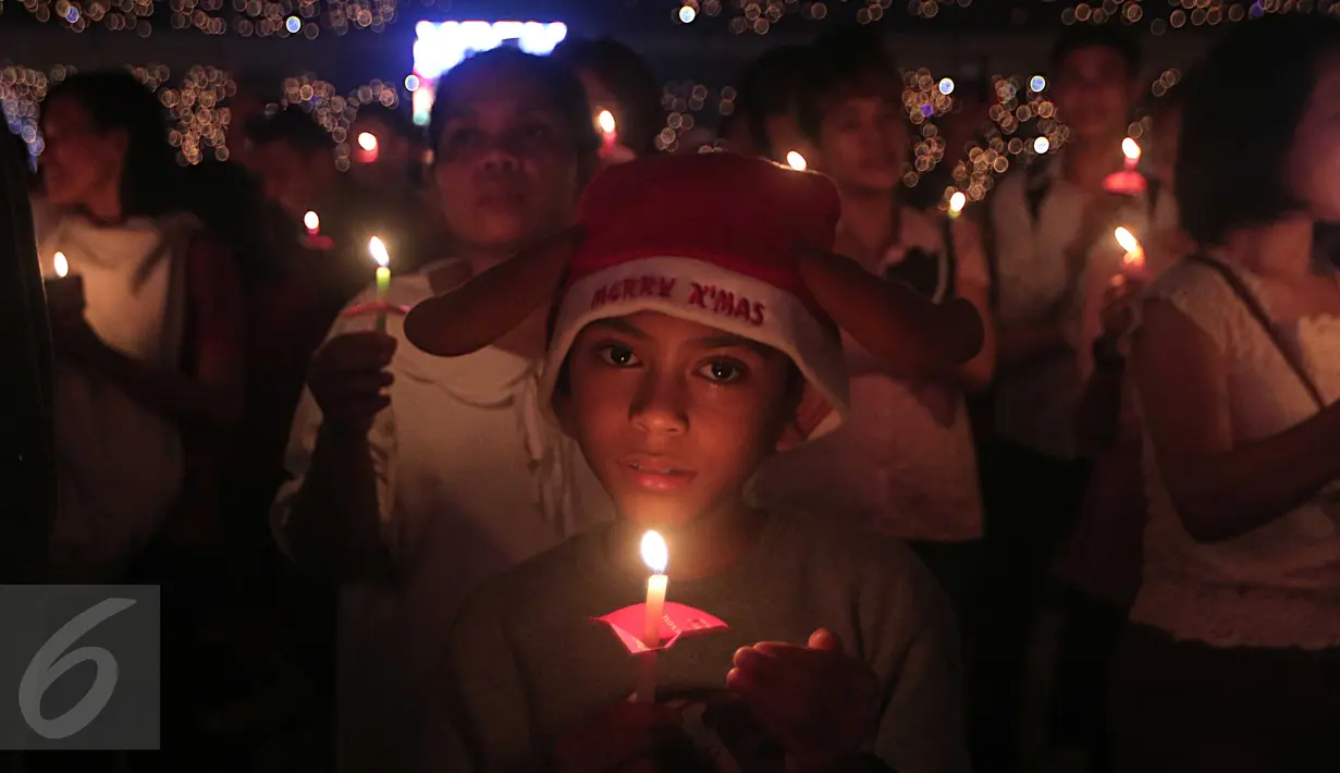 Seorang bocah laki -laki membawa lilin saat mengikuti perayaan Natal Gereja Tiberias di GBK, Jakarat, (5/12). Perayaan tema"Semua yang menerimanya, Diberinya kuasa untuk menjadi anak-anak Allah (Yohanes 1:12)".(Liputan6.com/Angga Yuniar)