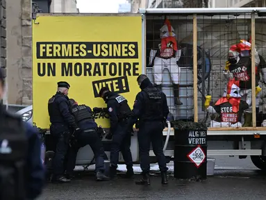 Petugas polisi Prancis saat berada di lokasi di mana para aktivis Greenpeace yang memblokir jalan dengan sebuah trailer saat demonstrasi menentang kebijakan pertanian dan mengecam dampak ekologis dari pertanian industri, di dekat Kementerian Pertanian di Paris, pada tanggal 20 November 2023. (Miguel MEDINA/AFP)