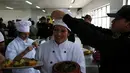 Petugas merapikan topi narapidana sebelum menyajikan masakannya dalam kompetisi kuliner 'INPE Mistura 2016' di penjara perempuan Chorrillos di Lima, Rabu (7/9). Sejumlah penjaga penjara memperhatikan dan mengawasi secara seksama. (REUTERS/Mariana Bazo)