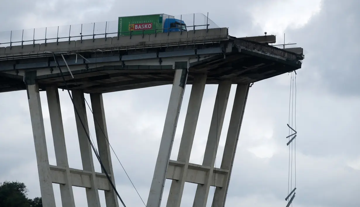 Sebuah truk berada di atas jembatan Morandi, dekat dengan bagian jalan layang yang runtuh, di Genoa, italia, Rabu (14/8). Insiden ambrolnya jembatan itu menyebabkan35 orang tewas dan mobil-mobil jatuh dari ketinggian sekitar 200 meter. (AFP/Valery HACHE)