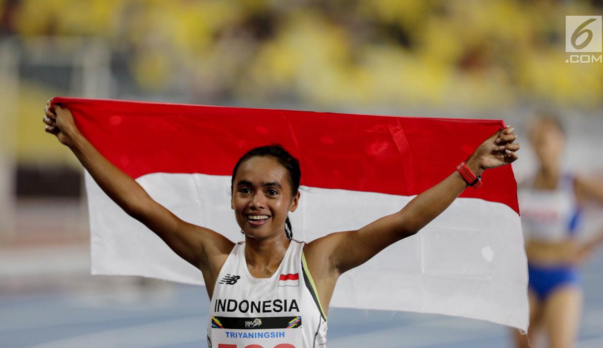 Pelari Indonesia Triyaningsih membawa bendera merah putih setelah mencapai garis finis dalam cabang olahraga atletik nomor lari 10 km putri SEA Games 2017 di Stadion Nasional Bukit Jalil, Malaysia, Kamis (24/8). (Liputan6.com/Faizal Fanani)