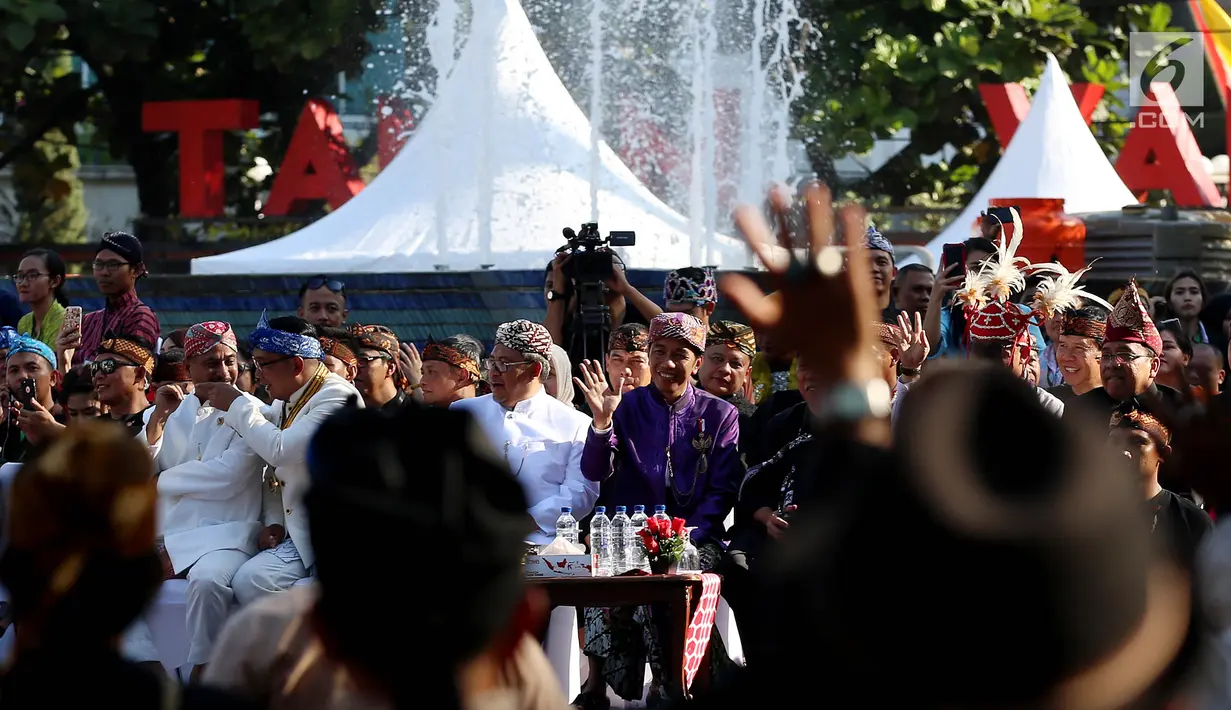 Presiden Joko Widodo (Jokowi) menyaksikan rombongan Karnaval Kemerdekaan Pesona Parahyangan yang melintas di Taman Vanda, Bandung,  Sabtu (26/8). Jokowi mengenakan setelan baju adat khas Sunda lengkap dengan iket kepala. (Liputan6.com/Johan Tallo)
