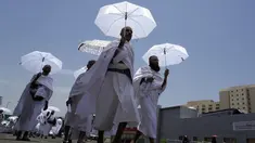 Jemaah haji berjalan sambil memegang payung di kamp tenda Mina, Makkah, Arab Saudi, Senin (26/6/2023). (AP Photo/Amr Nabil)