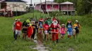 Relawan Jorge Alberto Barrozo, yang mengenakan kostum Sinterklas, berjalan untuk mengantarkan hadiah kepada anak-anak di komunitas tepi sungai di daerah pedesaan Careiro da Varzea, negara bagian Amazonas, Brasil pada Sabtu 20 Desember 2025. (Michael DANTAS/AFP)
