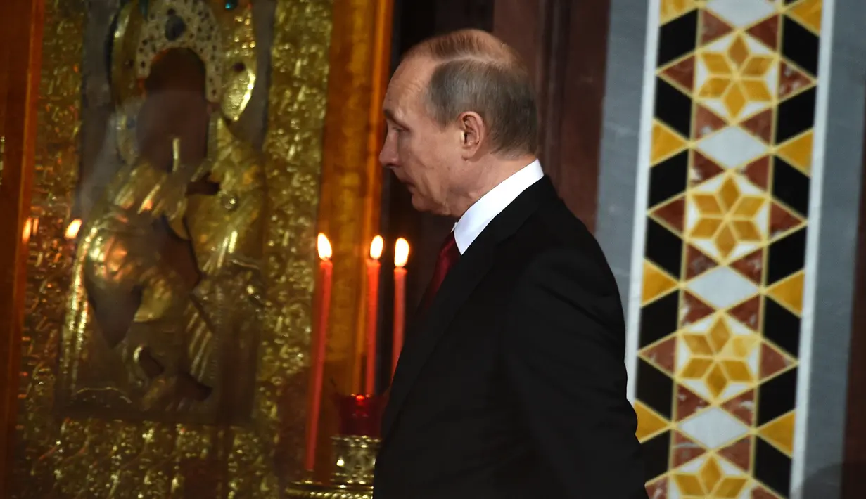 Presiden Rusia, Vladimir Putin saat mengikuti prosesi Paskah Ortodoks di Gereja Katedral Kristus Juru Selamat di Moskow, Rusia,(16/4). (AFP Photo / Vasily Maximov)