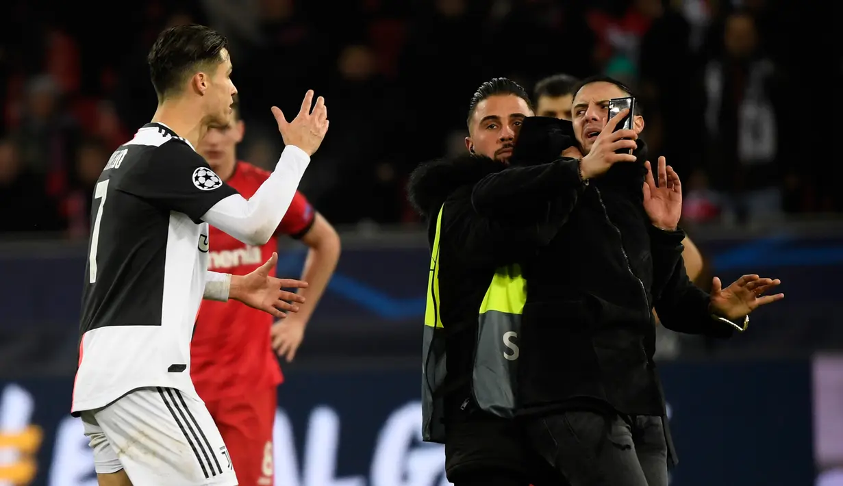 Pemain Juventus Cristiano Ronaldo (kiri) berdebat dengan seorang penyusup yang masuk ke lapangan usai laga Liga Champions antara Juventus melawan Bayer Leverkusen di Bay Arena, Leverkusen, Jerman, Rabu (11/12/2019). (INA FASSBENDER/AFP)