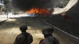 Petugas berjaga saat pembakaran ganja dan obat terlarag lainnya di kamp angkatan darat, Tijuana, Meksiko, (18/8/2015). 7 ton obat terlarang yang disita di Tijuana akan dibakar secara bersamaan di sembilan negara bagian di Meksiko. (REUTERS/Jorge Duenes)