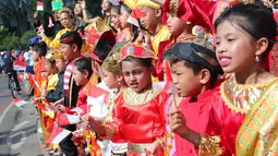 Antusias murid sekolah minggu Gereja Eban Haezer mengenakan baju adat sambil melambaikan bendera nasional di Bundaran HI Jakarta, Minggu (21/8). Menyanyikan lagu Indonesia Raya dan lagu daerah, mereka memperingati HUT RI ke 71. (Liputan6.com/Angga Yuniar)